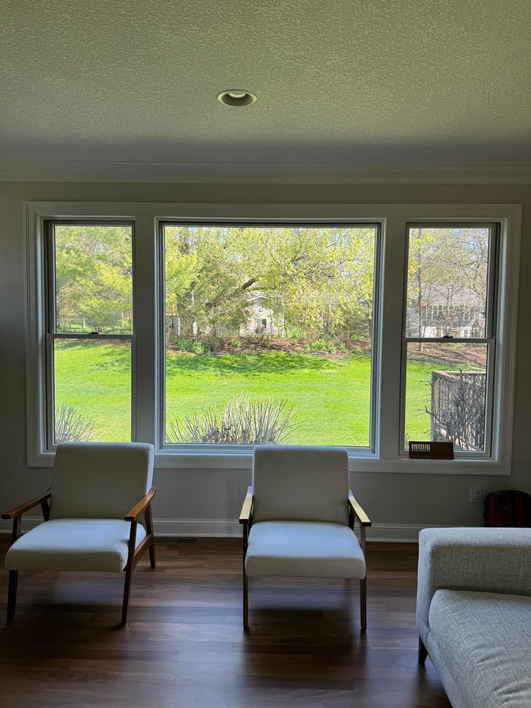 A living room with three chairs and a couch and a large window