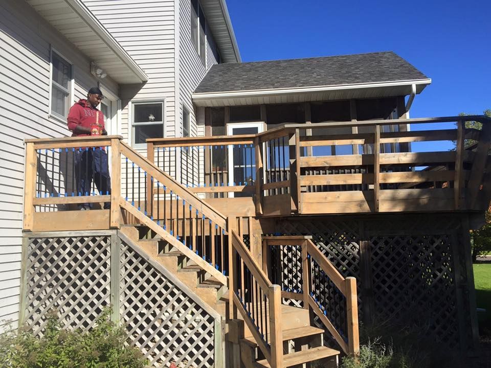 A man standing on a wooden deck next to a screened in porch