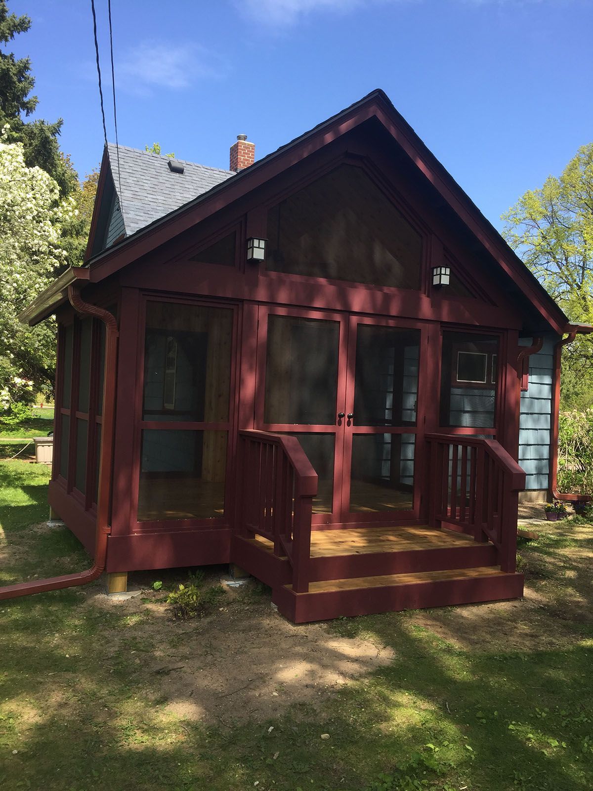 A small red house with a screened in porch and stairs