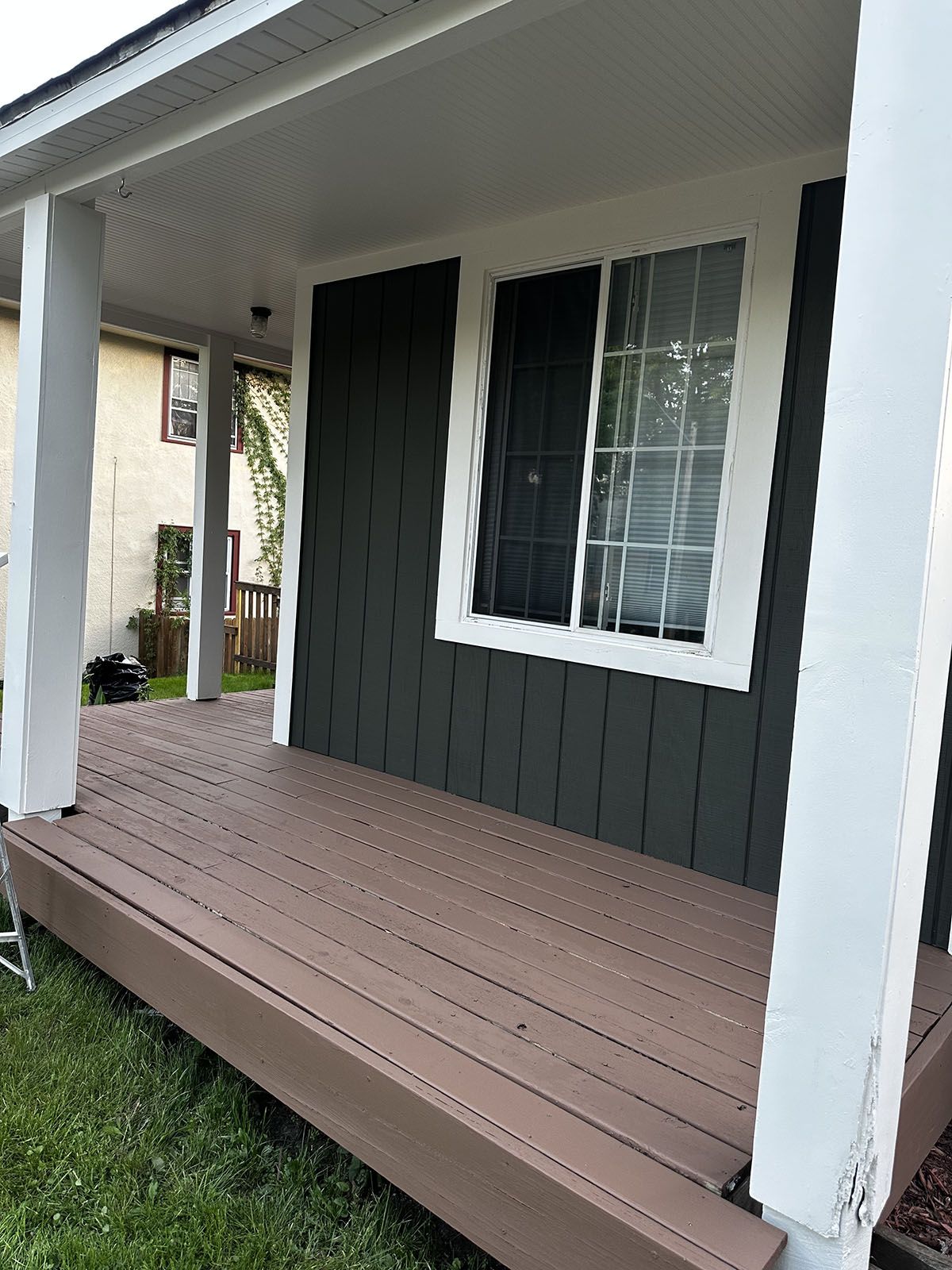 A porch with a wooden deck and a window on the side of a house.