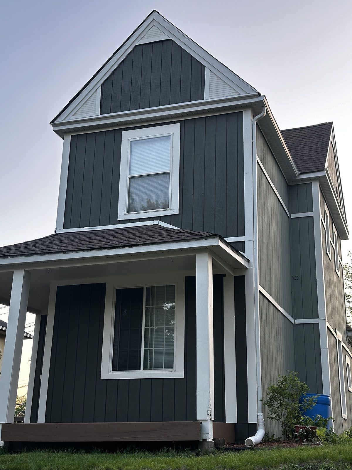 A black house with white trim and a porch
