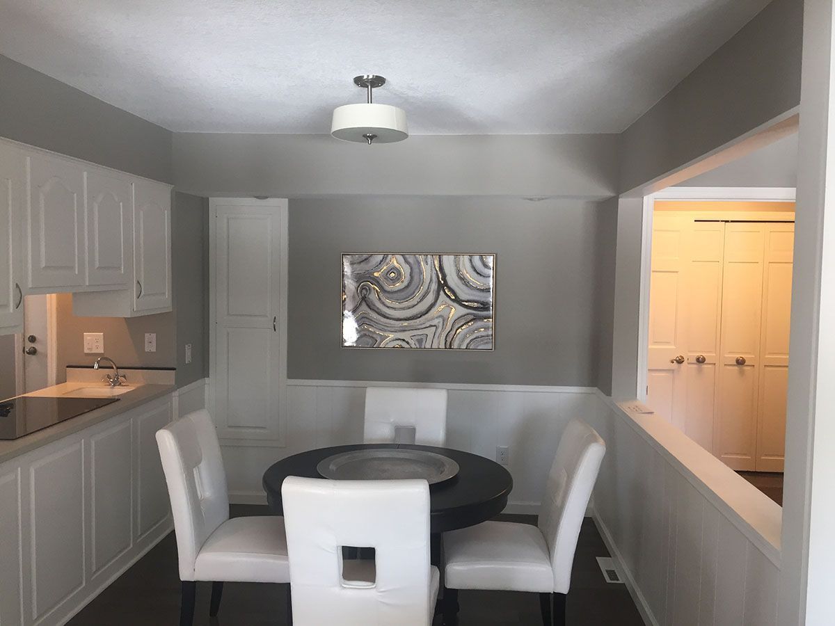 A dining room with a round table and white chairs