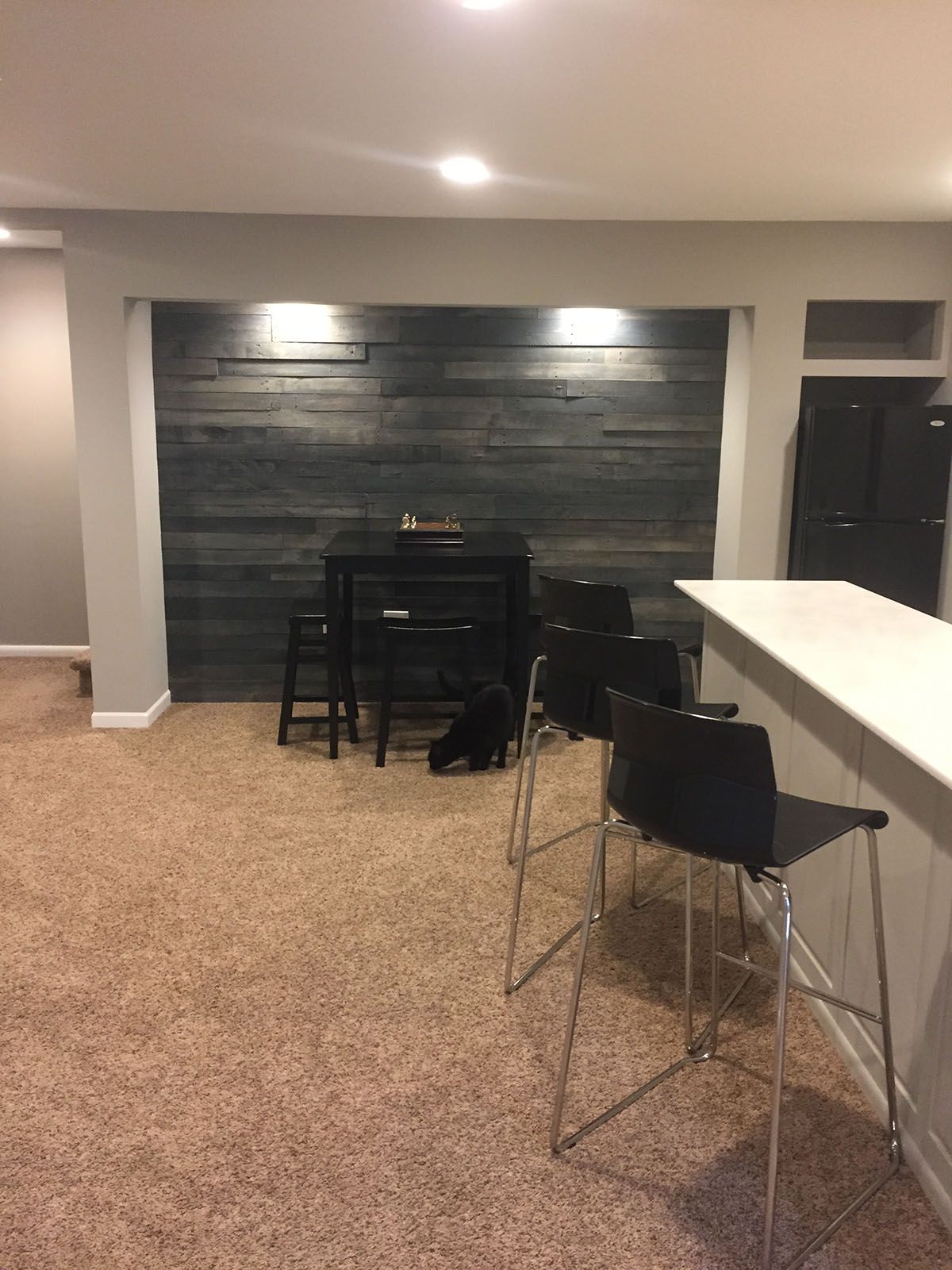 A basement with a table and chairs and a dog laying on the floor.