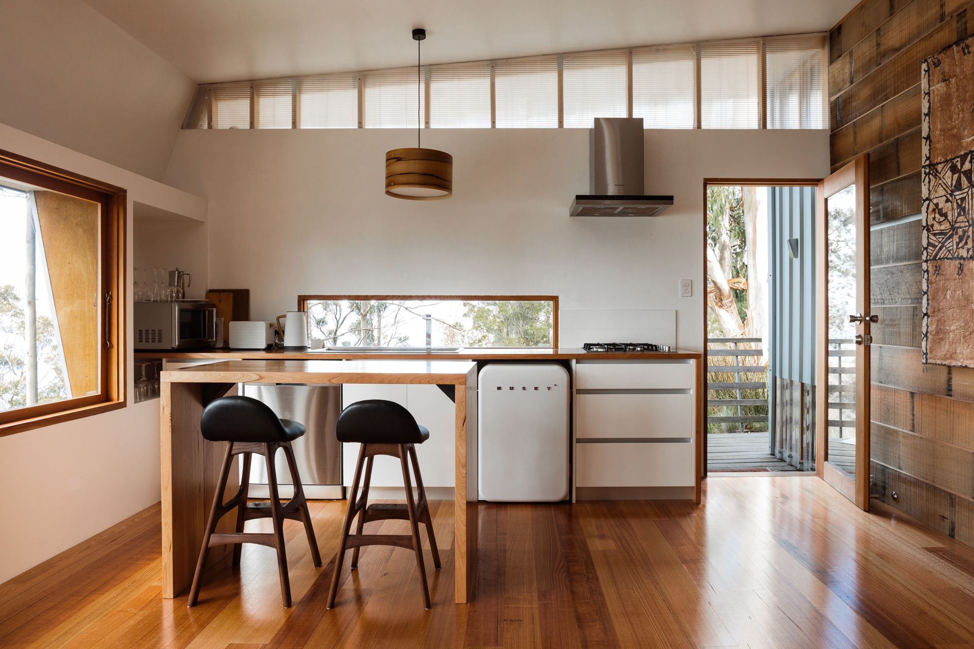 A kitchen with wooden floors and stools in it