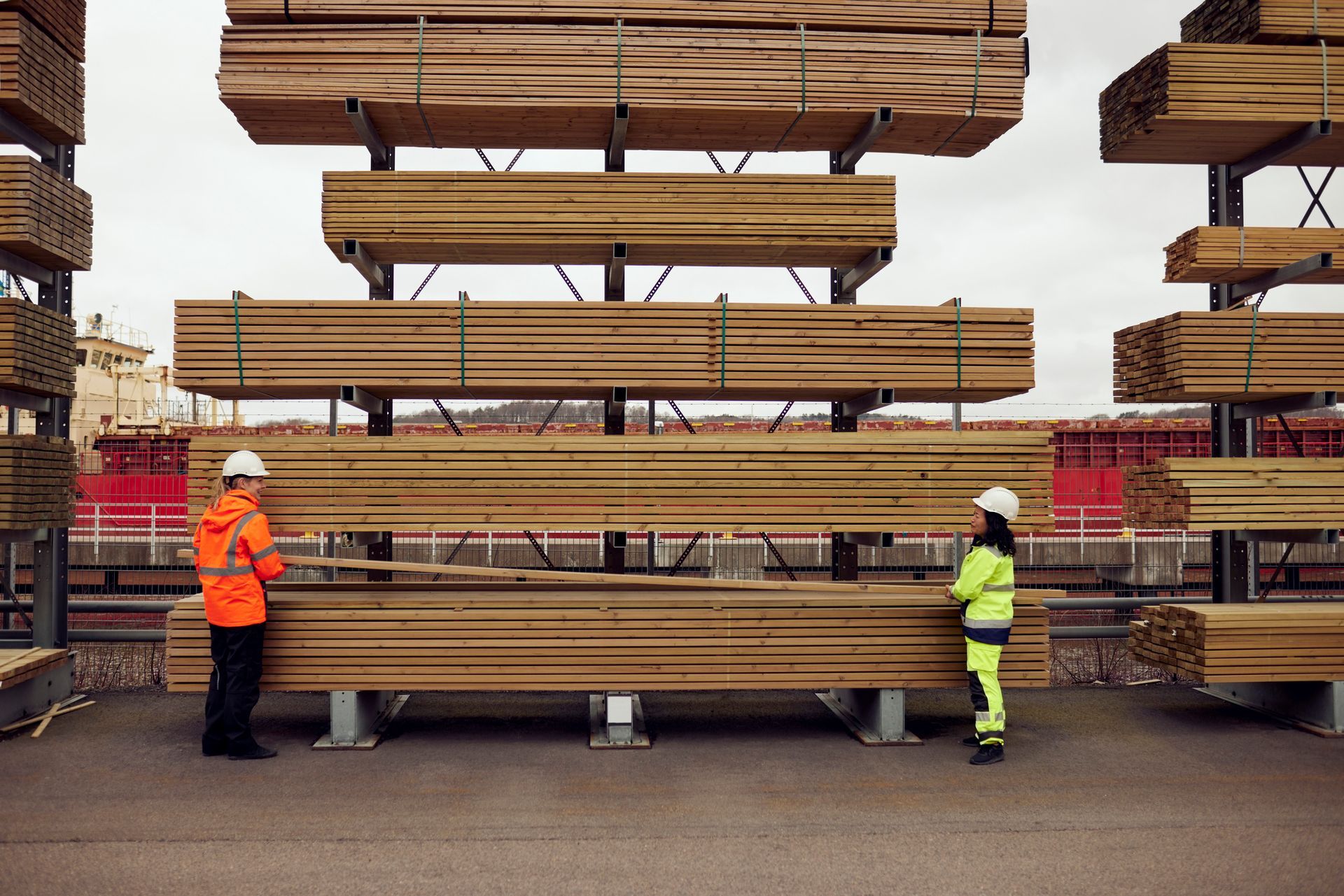 Workers handling Tasmanian timber planks at outdoor lumber storage yard.