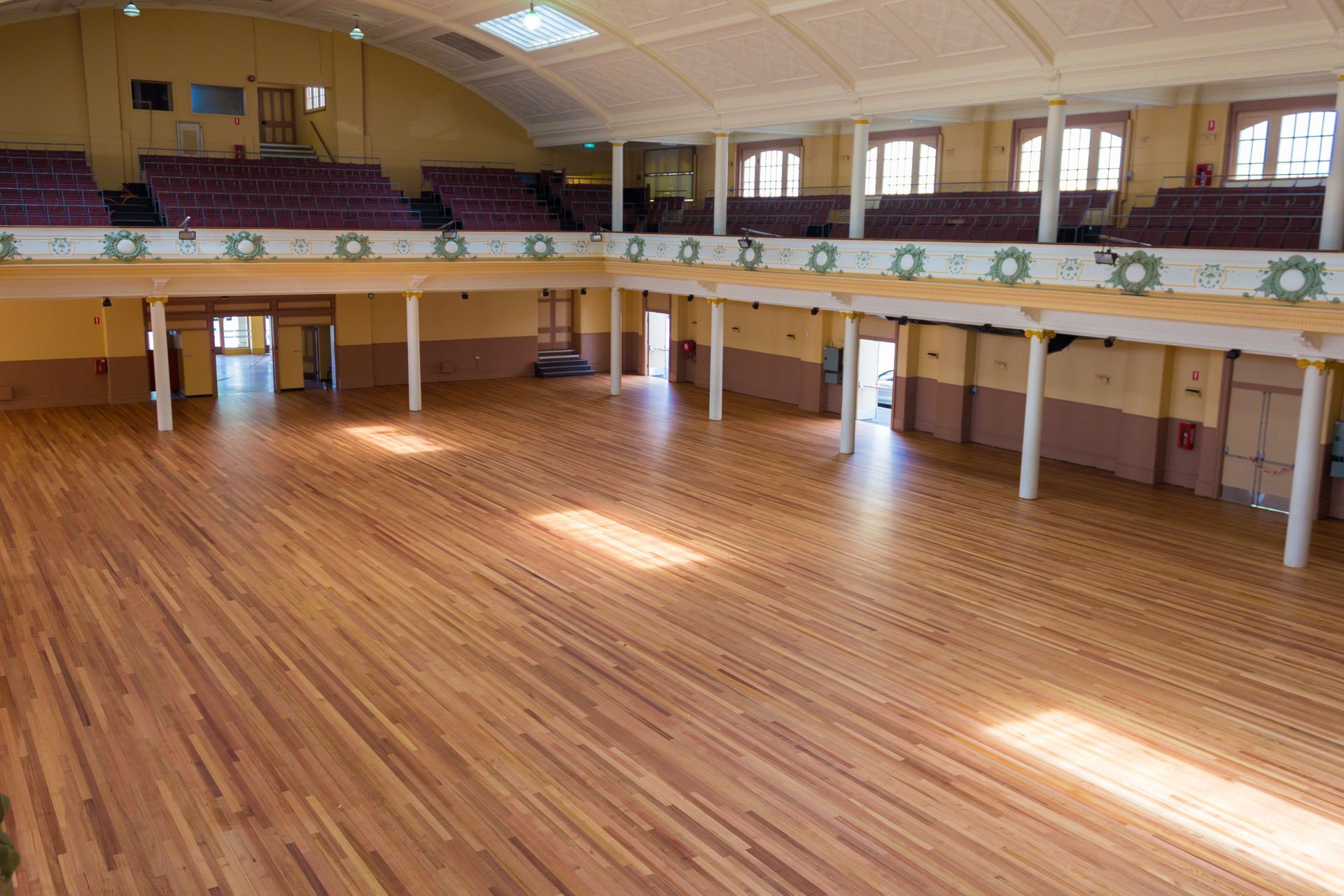 A large empty auditorium with a wooden floor and purple seats.