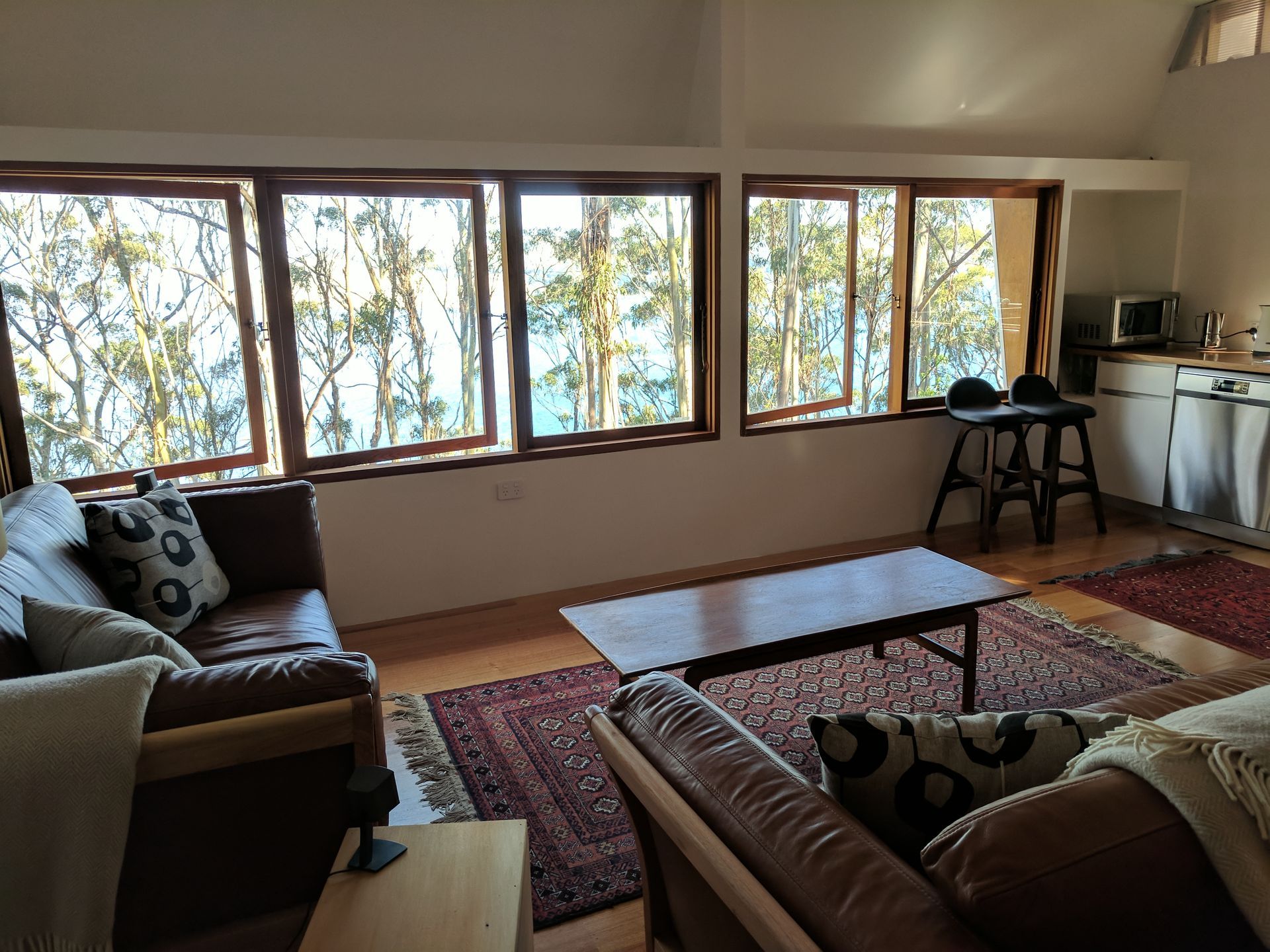 A living room with a couch and a table and lots of windows