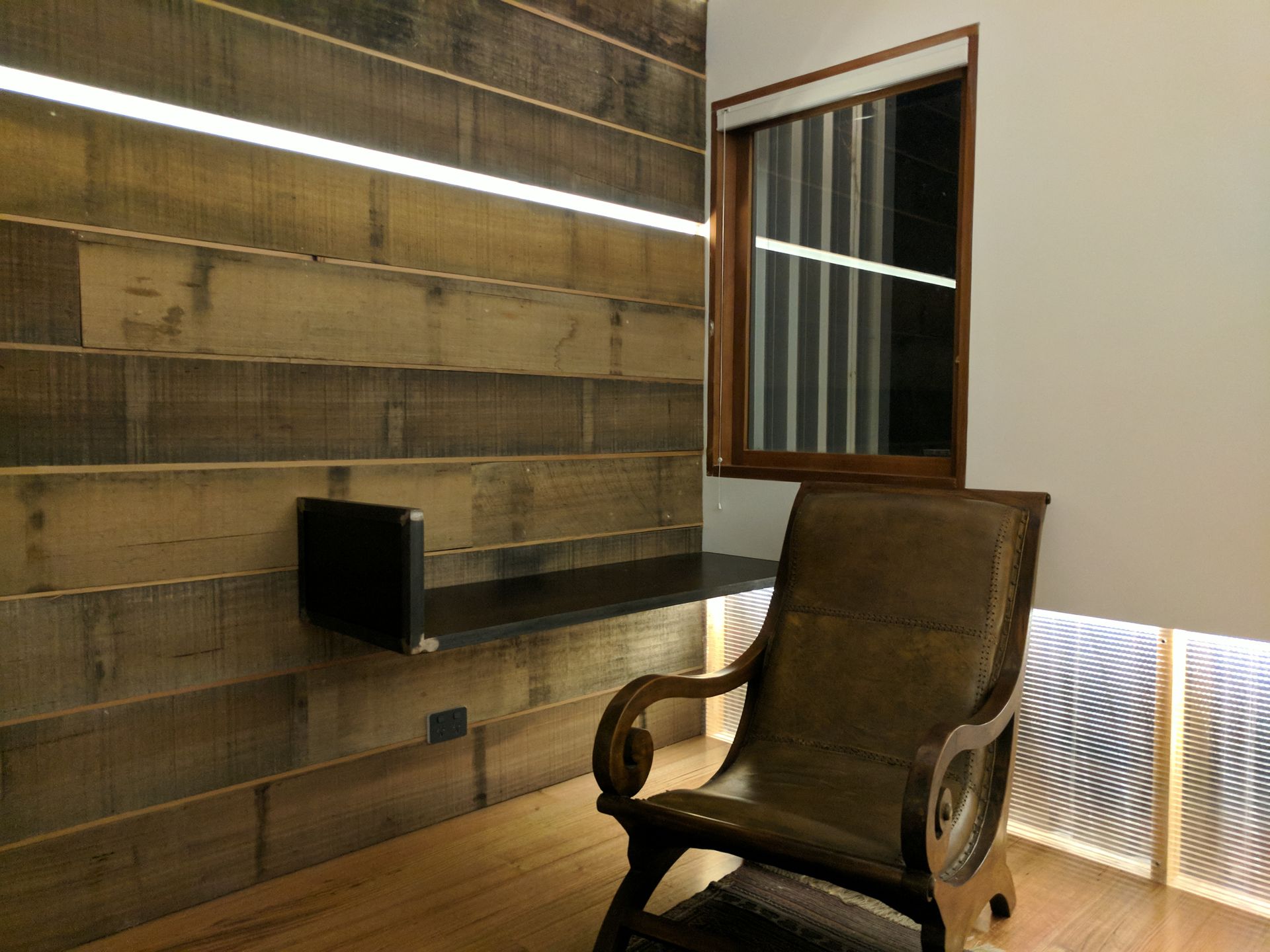 A chair is sitting in a room with a wooden wall and a window.