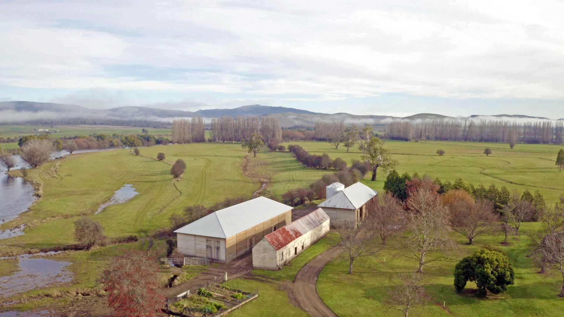 An aerial view of a farm with a river in the background.