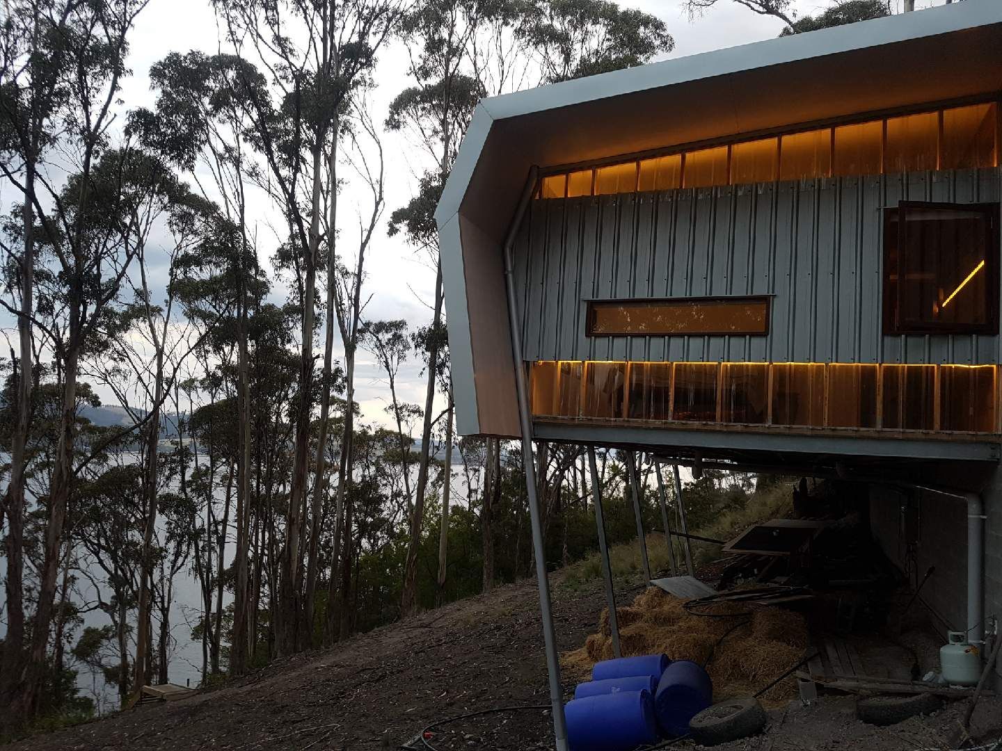 A house is sitting on a hill overlooking a body of water surrounded by trees.