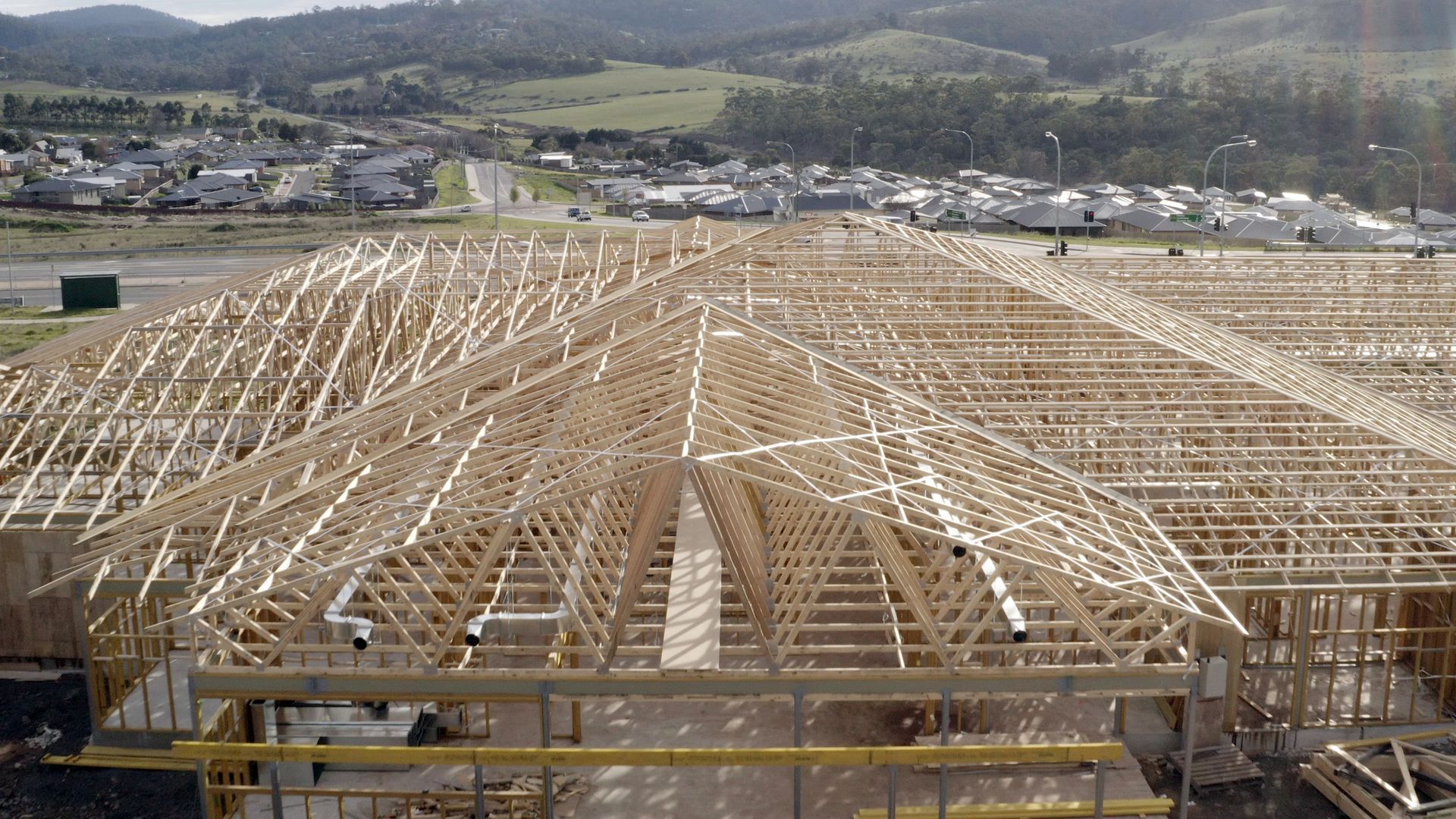 A large wooden structure is being built with mountains in the background.