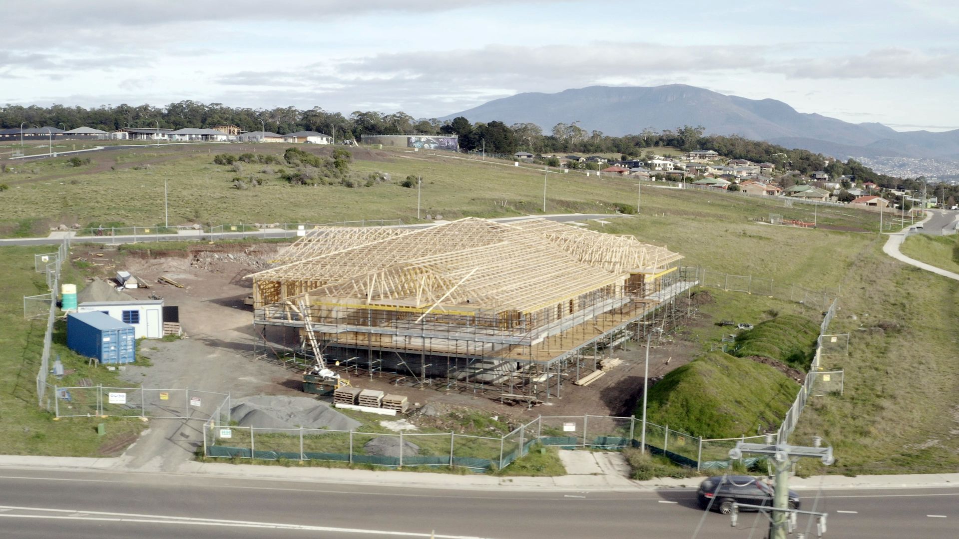 An aerial view of a building under construction in a field with mountains in the background.