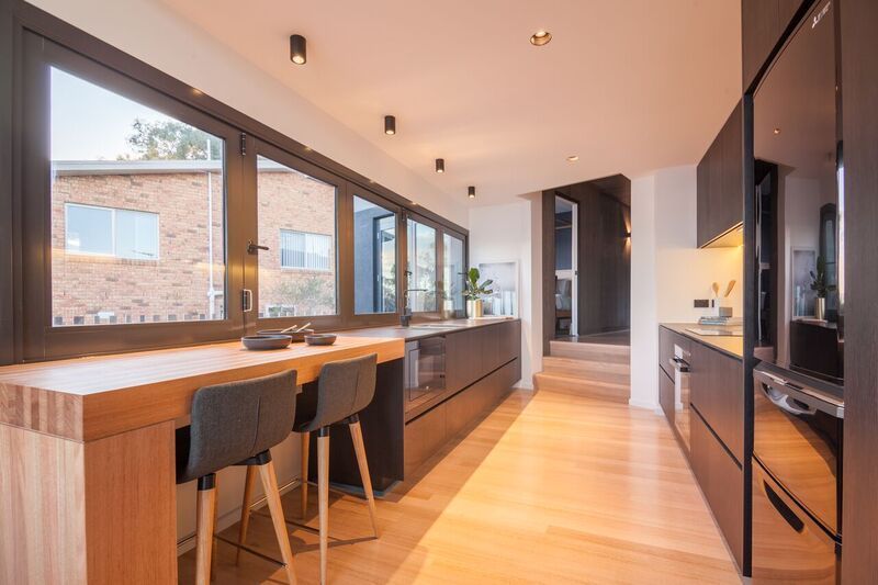 A General Interior View of a Large Grey Fitted Kitchen with Wooden Breakfast Bar Island | Glenorchy, TAS | McKay Timber