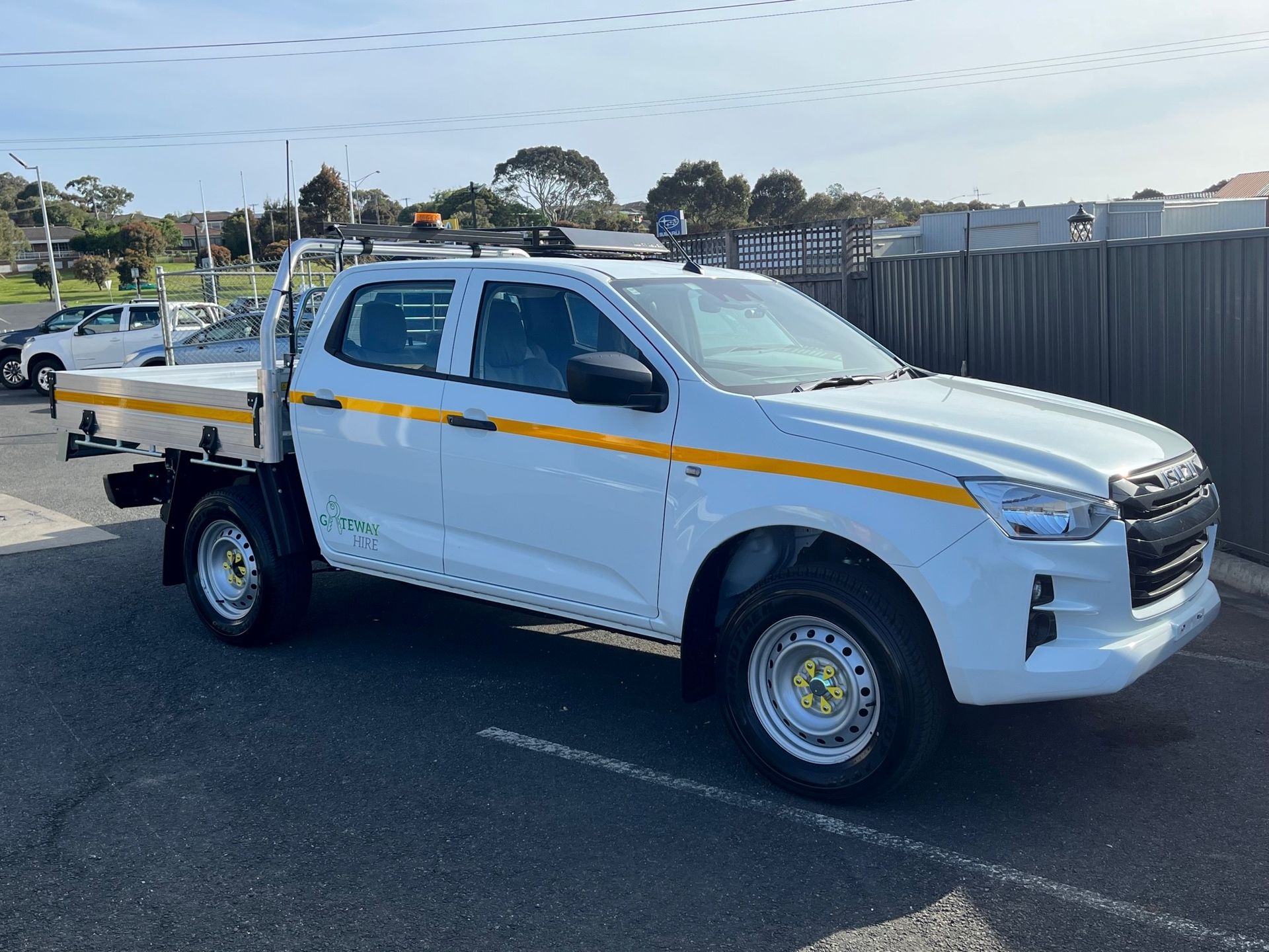 a white truck with a yellow stripe on the side is parked in a parking lot .