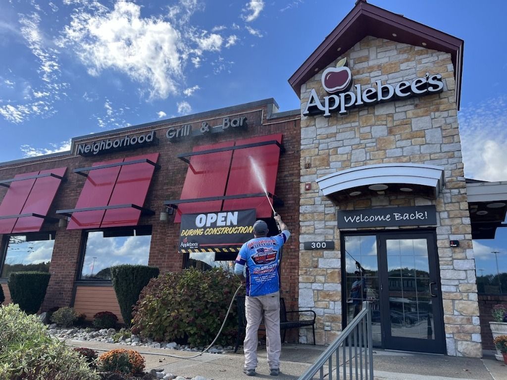 J & M Power Washing - Man power washing the exterior of an Applebee's restaurant on a sunny day.