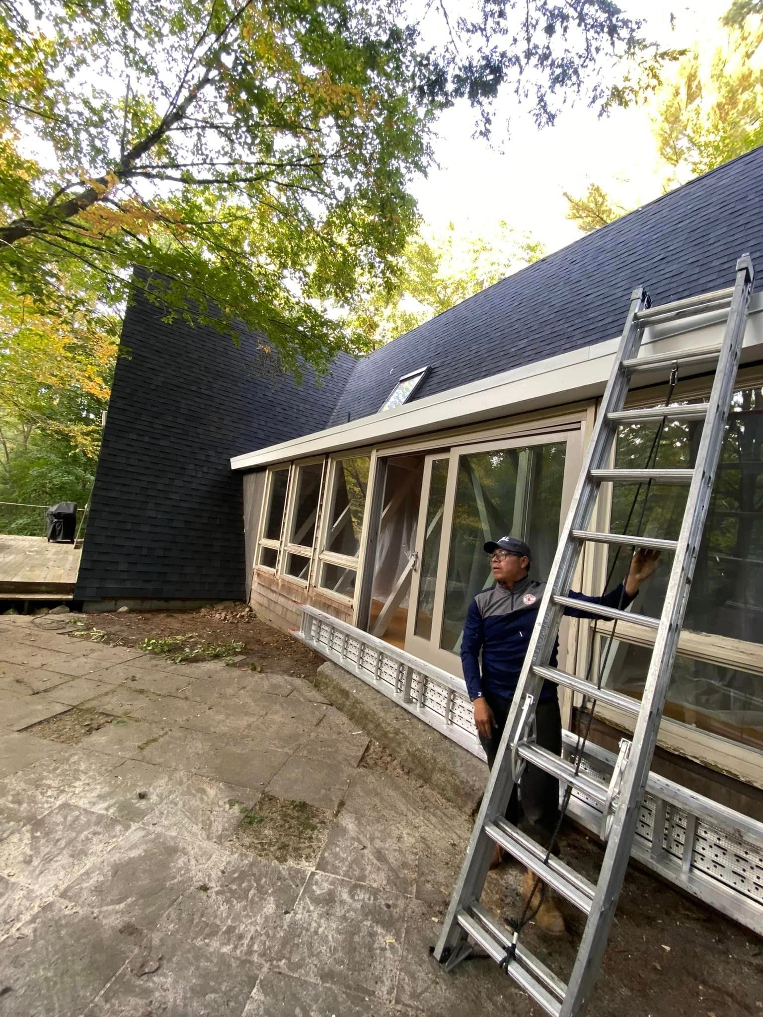 A man is standing next to a ladder in front of a house under construction.