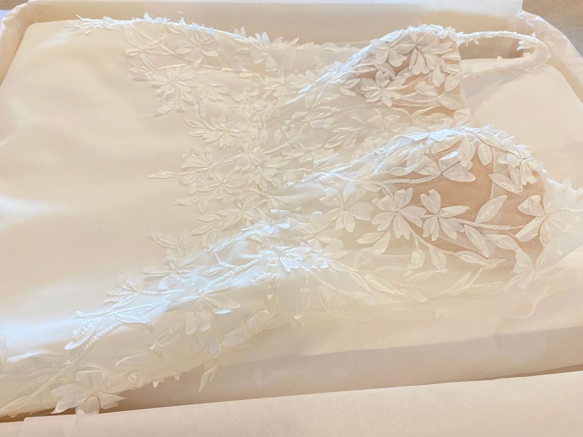 White lace bridal gown detail on satin in a box.
