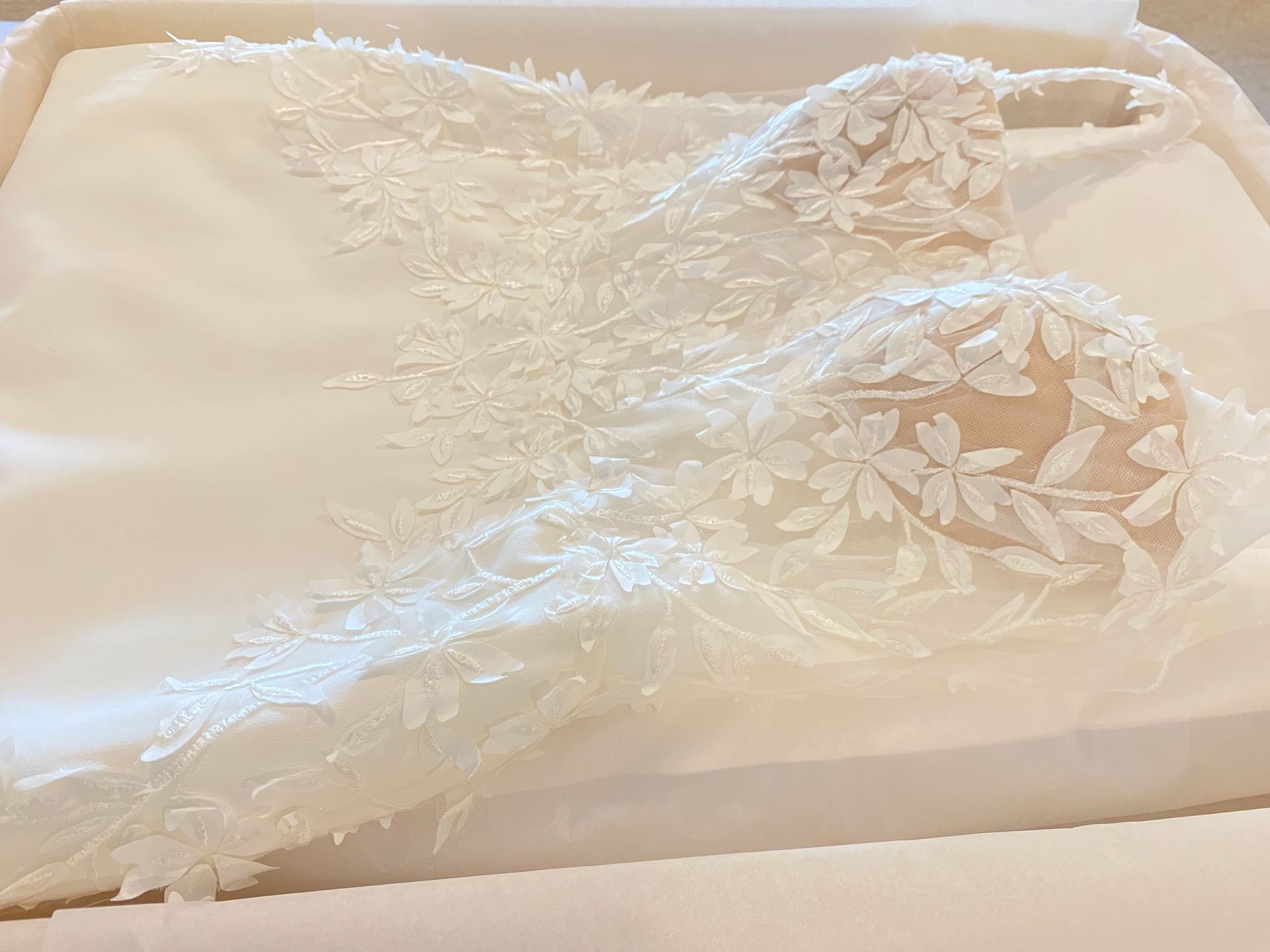 White lace bridal gown detail on satin in a box.