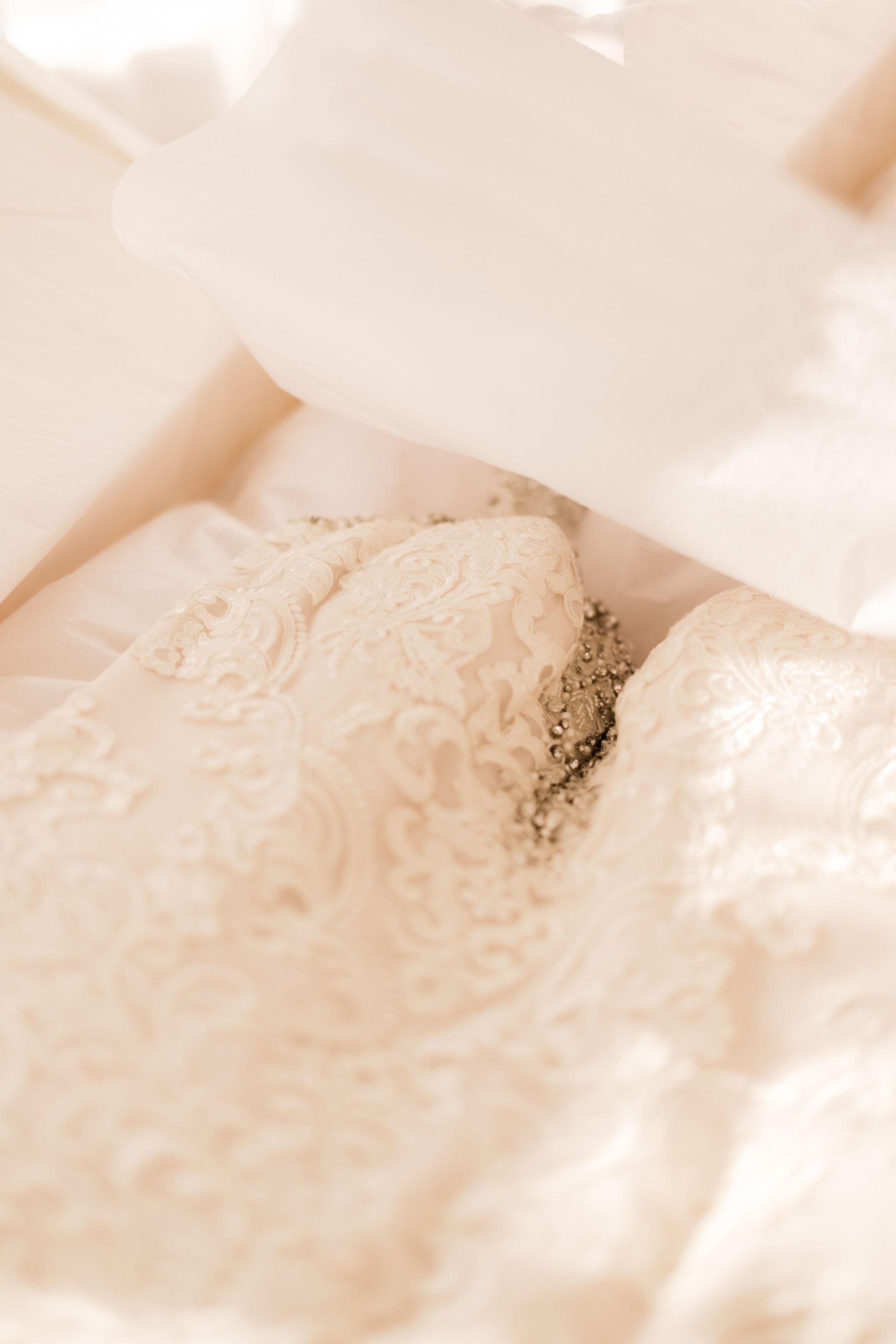 Cream-colored lace lingerie on a bed with soft, white pillows.
