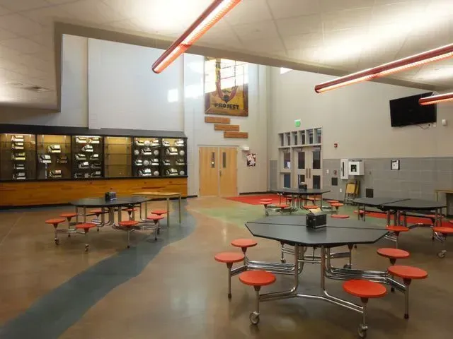 The inside of a school cafeteria with tables and benches.