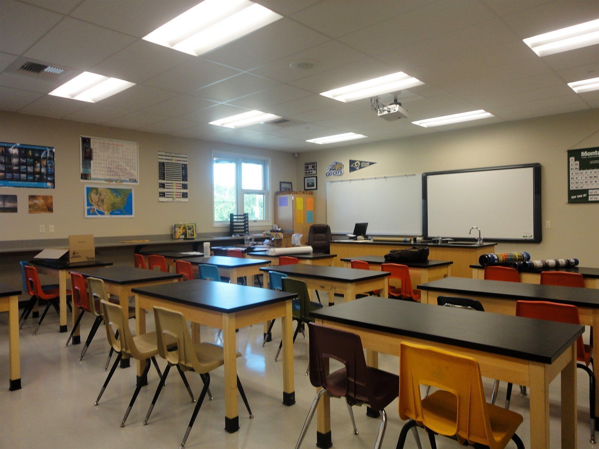 A classroom with tables and chairs and a white board.