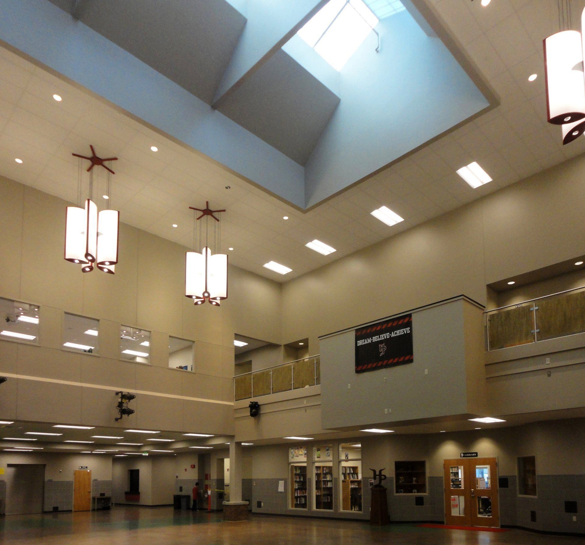 Spacious atrium with high ceilings, skylight, and modern pendant lights. 