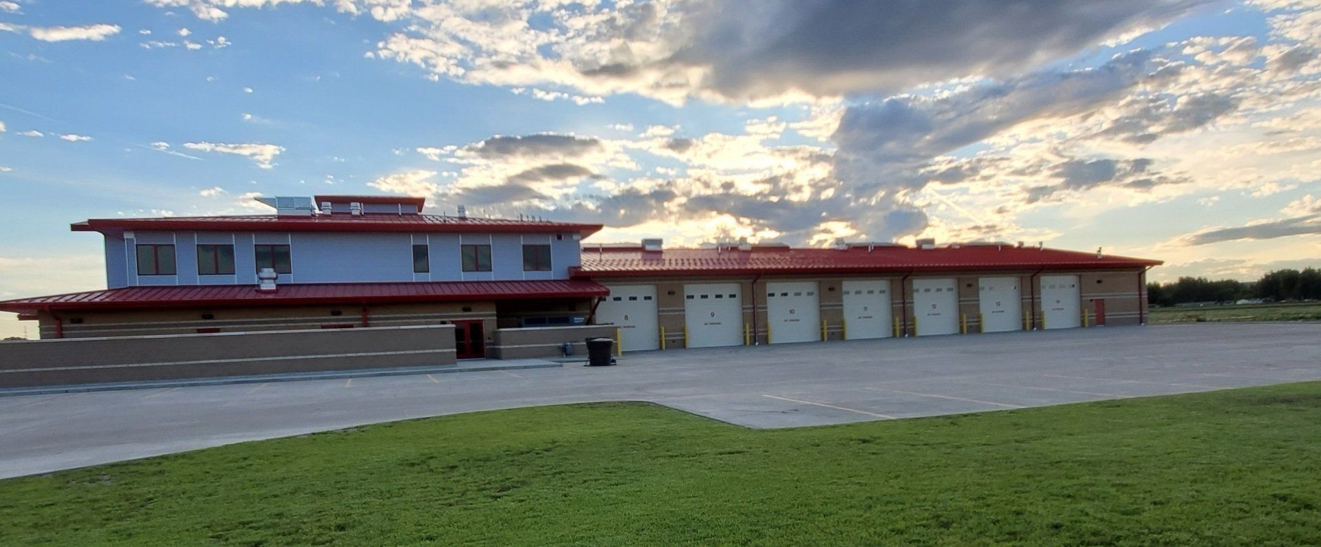 A large house with a red roof is sitting on top of a lush green field.