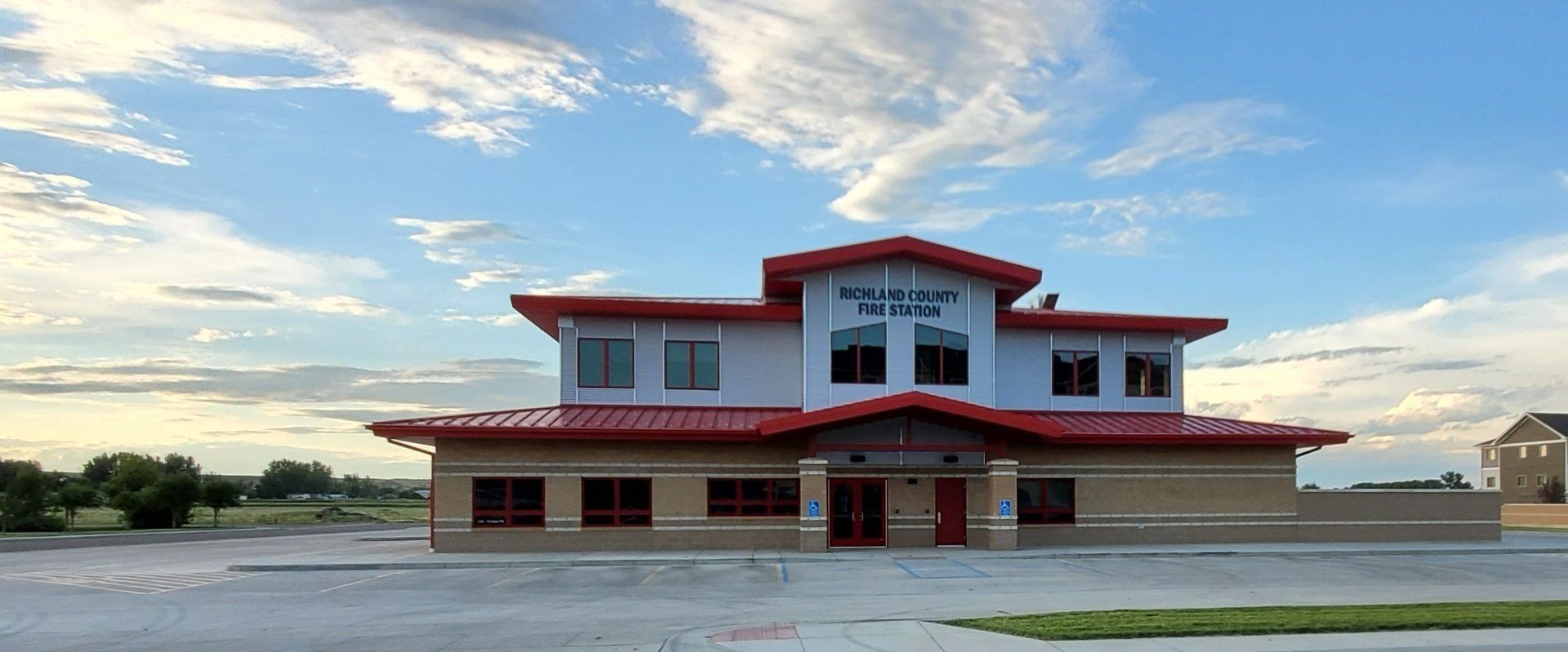 Two-story fire station with tan brick and red roof.