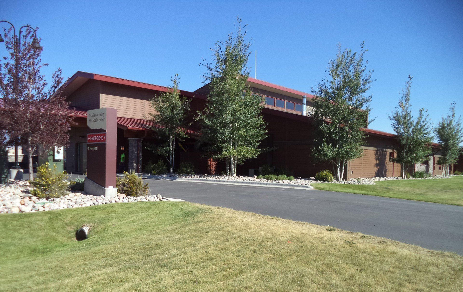 Modern library building with a slanted roof, surrounded by trees.
