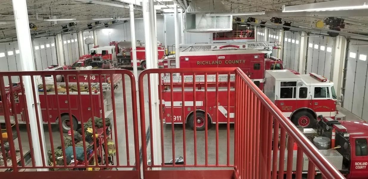 A fire truck is parked in a garage next to a railing.