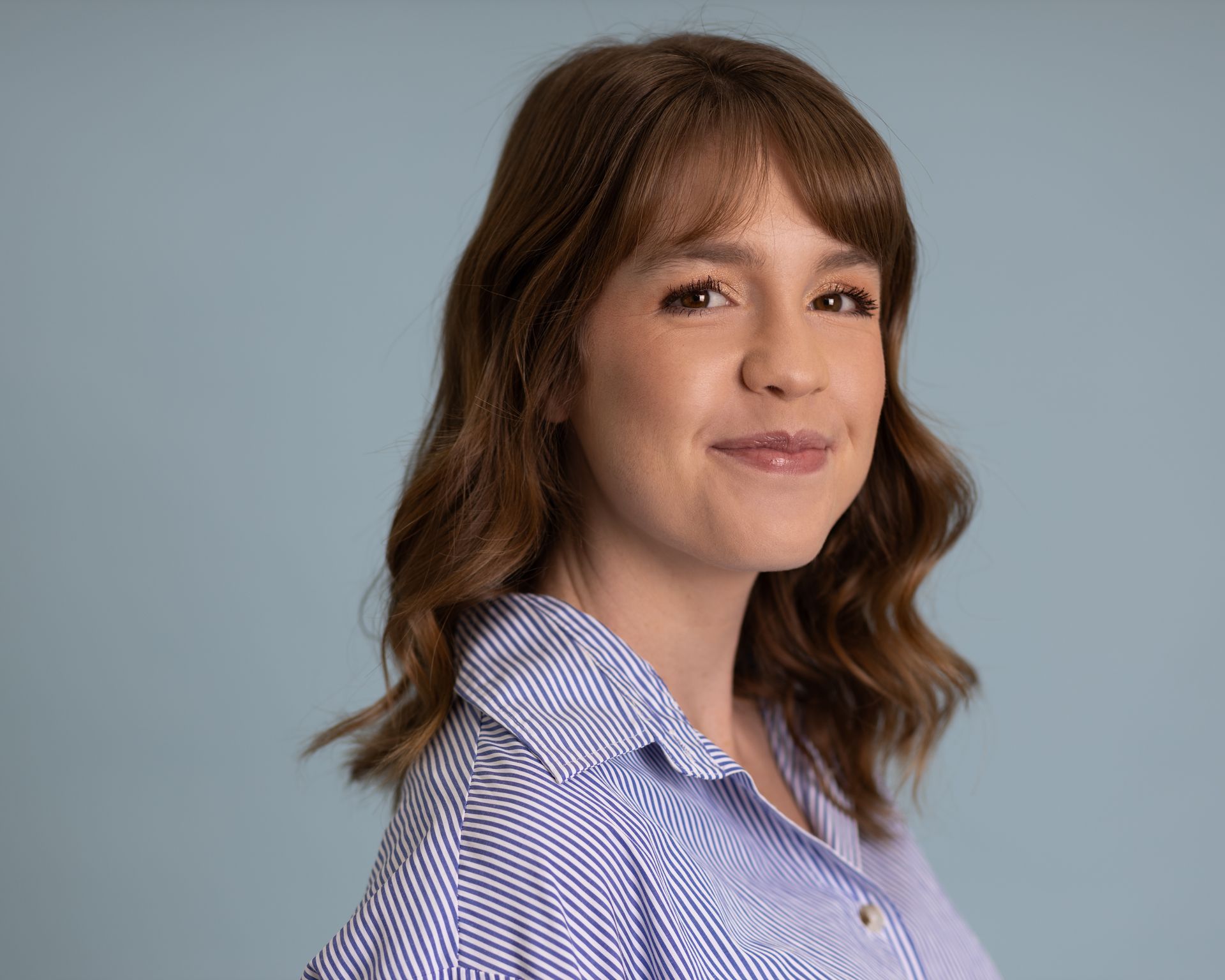 A woman in a black dress is holding a man 's hand in the woods.