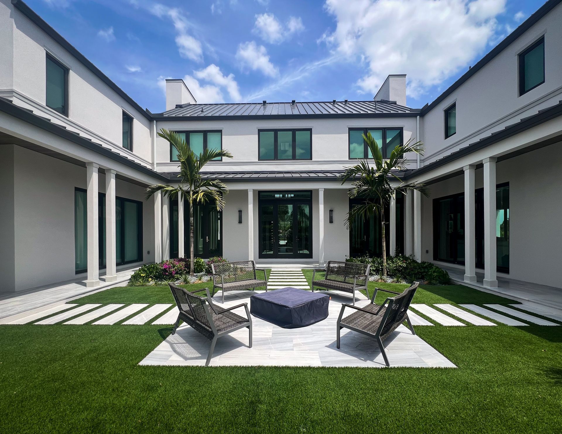 Wellington home with fire pit, outdoor seating, artificial turf, pavers, and palm trees.