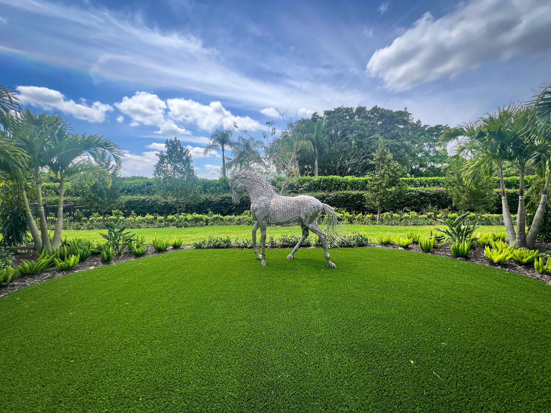 Wellington home with horse sculpture, artificial, and palm trees.