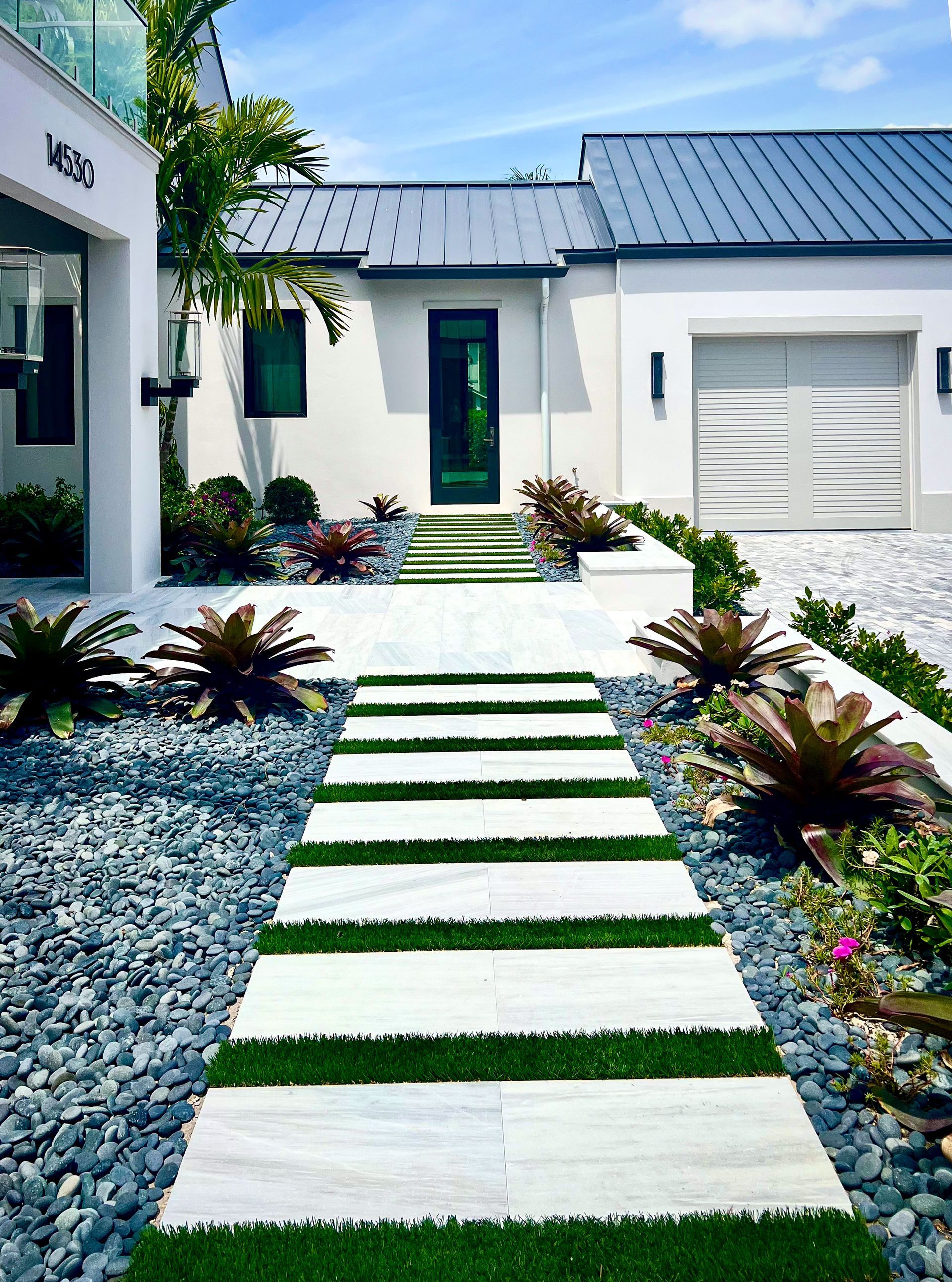 Wellington home with paver entrance, artificial turf, and bromeliads.