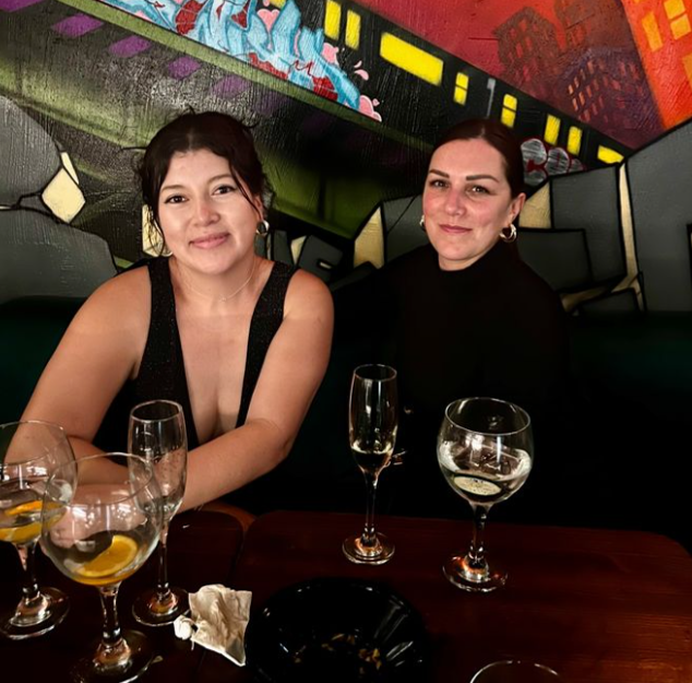 Two women are sitting at a table with wine glasses