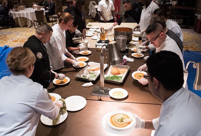 A group of people are sitting around a table preparing food.