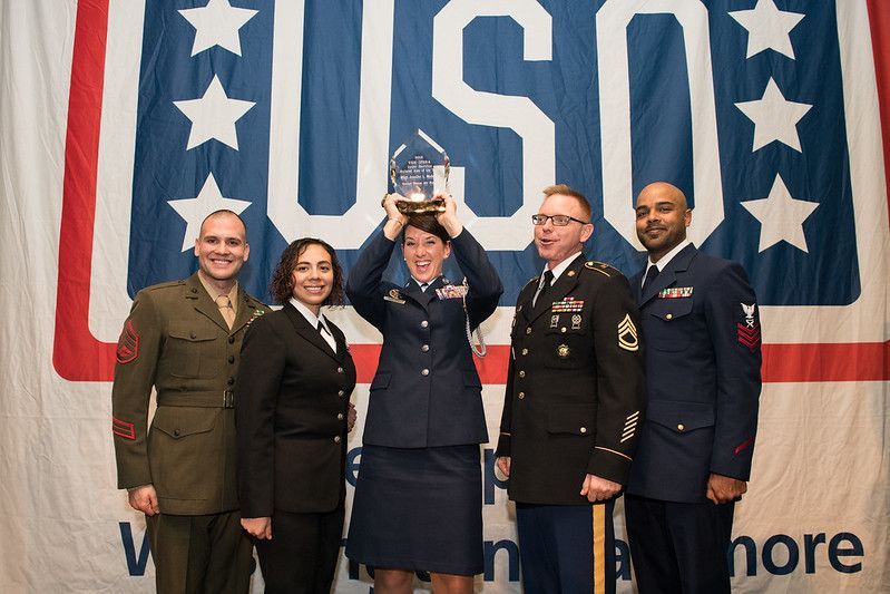 A group of people in military uniforms standing in front of a us army banner