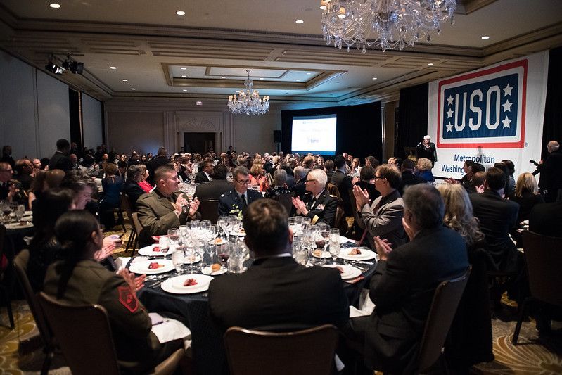 A large group of people are sitting at tables in a large room.