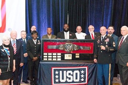 A group of people are posing for a picture in front of a uso sign