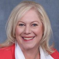 A woman in a red jacket and white shirt is smiling for the camera.