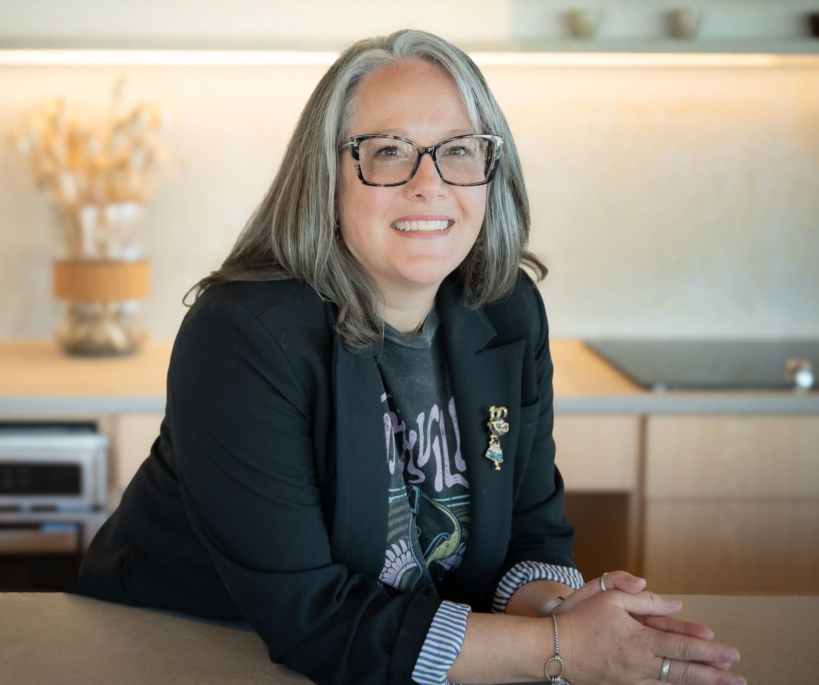A woman in a black jacket is smiling for the camera while sitting at a table.
