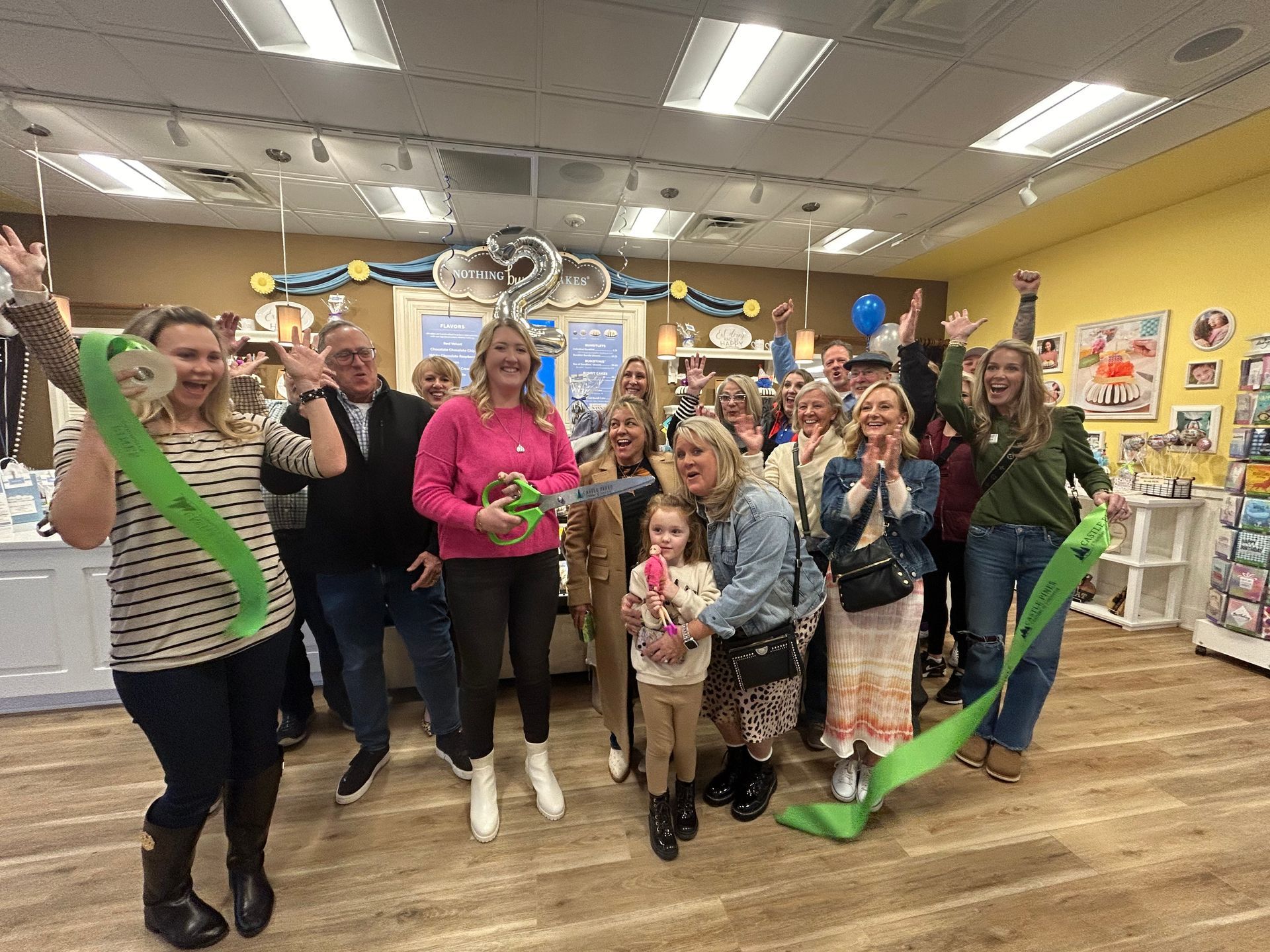 A group of people are standing in a room holding green ribbons.