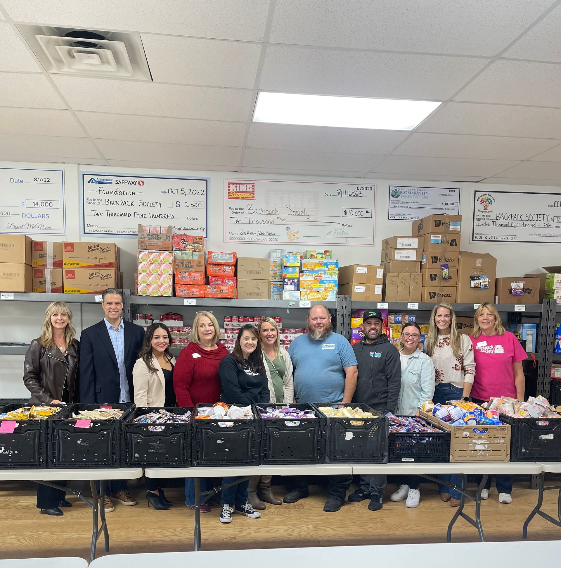 A group of people are posing for a picture in front of a table full of boxes