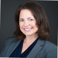 A woman in a suit and blue shirt is smiling for the camera.