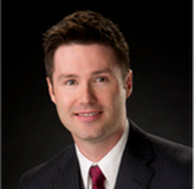 A man in a suit and tie is smiling for the camera