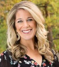 A woman in a floral shirt is smiling for the camera.
