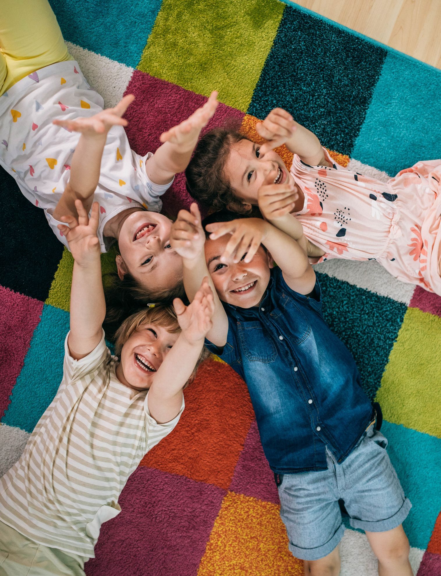 a group of children are laying on a colorful rug .