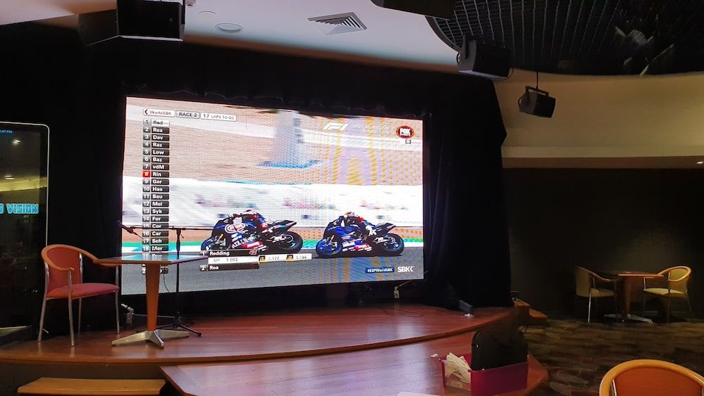A Large Screen Shows a Motorcycle Race on a Stage — Inspired Audio Visual in Coffs Harbour, NSW