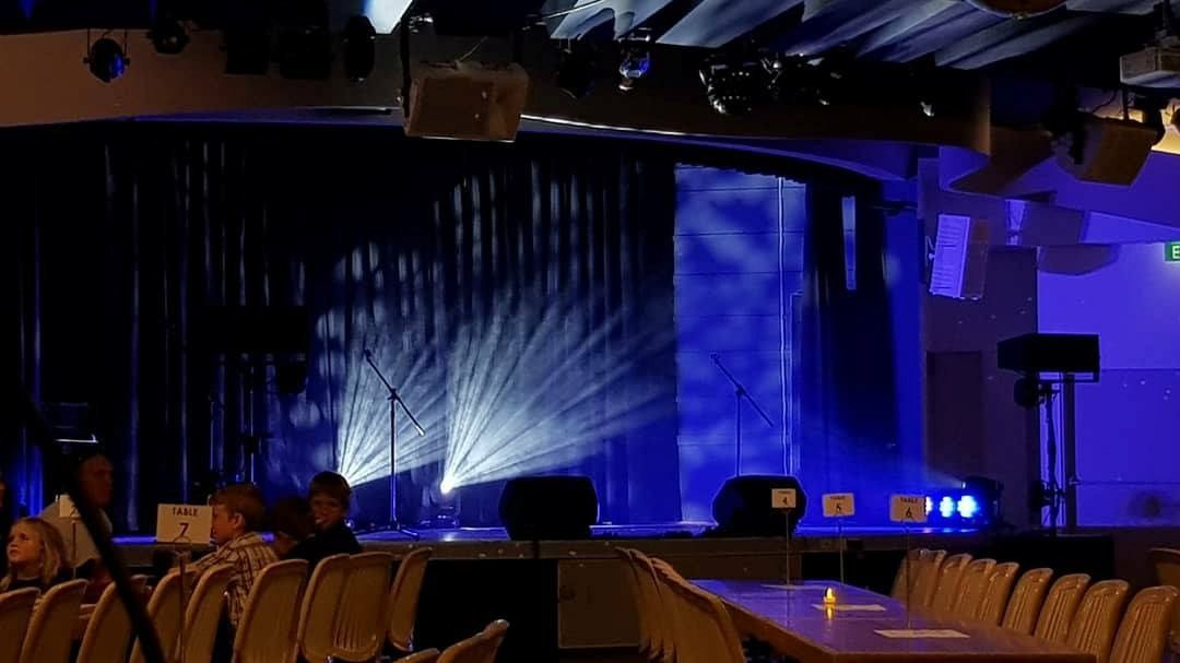 A Dark Room With a Table and Chairs in Front of a Stage — Inspired Audio Visual in Coffs Harbour, NSW