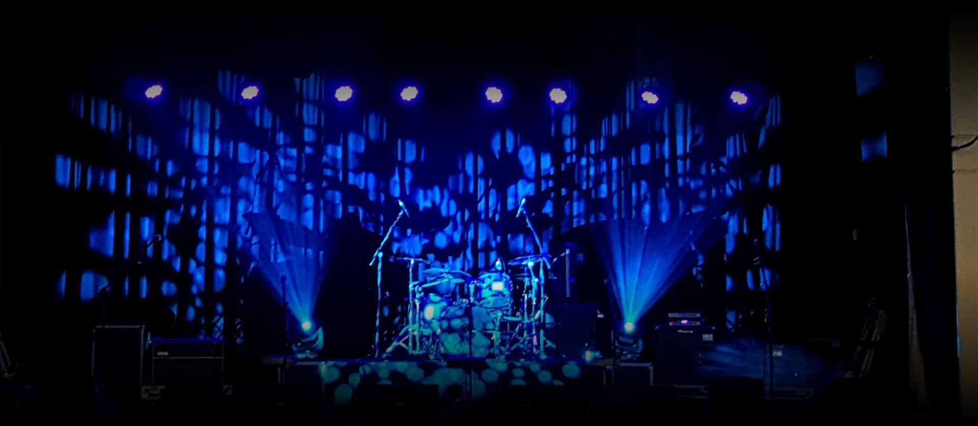 A Drum Set is on a Stage With Blue Lights — Inspired Audio Visual in Coffs Harbour, NSW